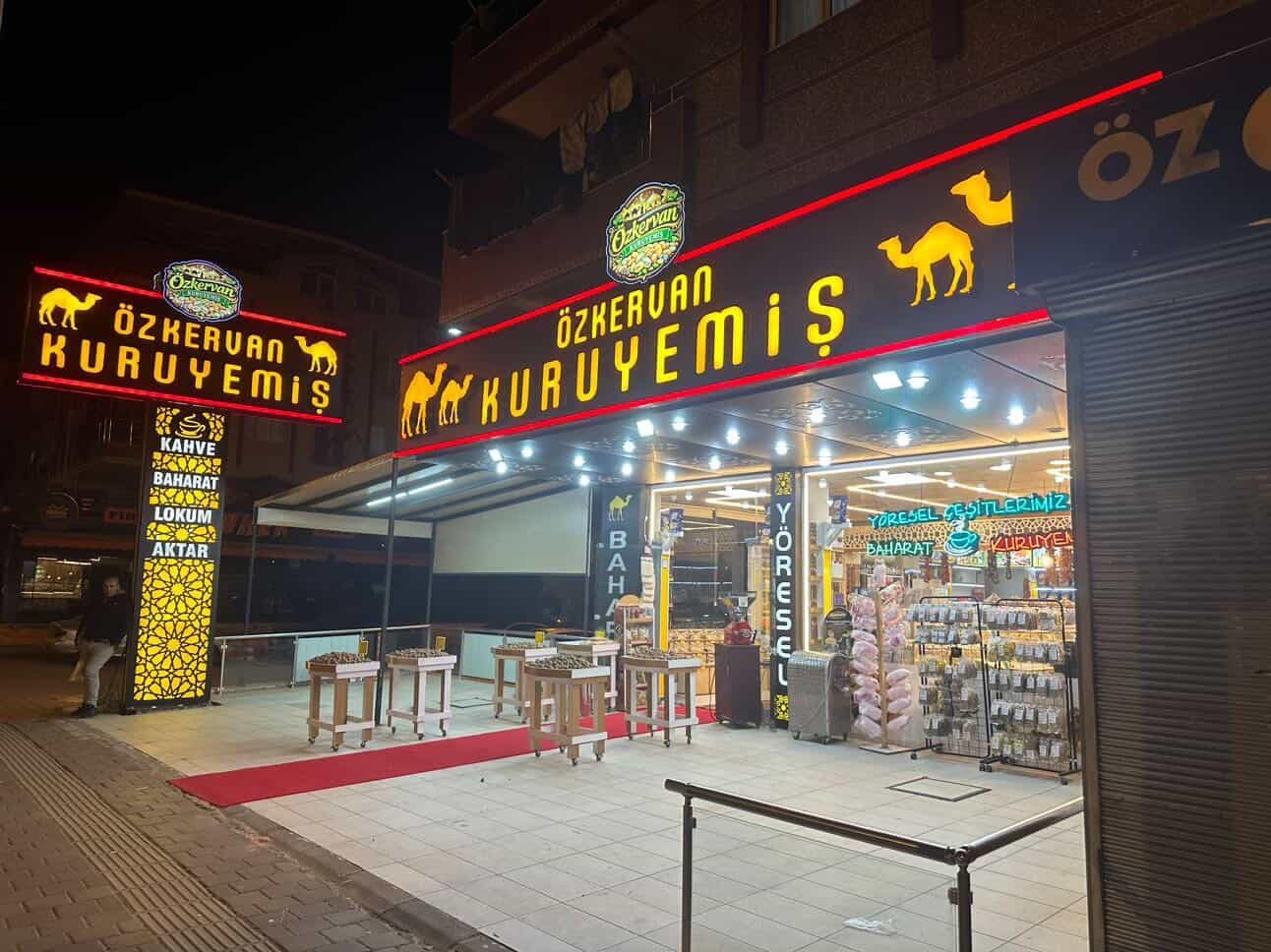 Öz Kervan Kuruyemiş dükkanının cephesi, akşam ışıklarıyla